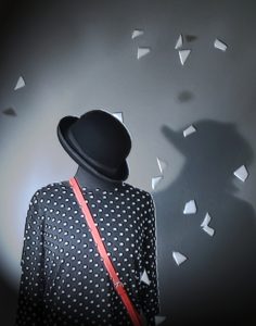 Foto di un manichino da sarta in mezzo ritratto, con un vestito bianco e nero, un cappello nero e una borsa rossa. Fiocchi di neve bianchi tridimensionali di circa 3 cm cadono dall'alto. Foto: Leopoldi-Art.